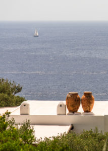 Sicily - Sunny impressions of the Aeolian Islands, also known as Aeolian Islands or Isole Eolie: Lipari, Stromboli, Salina, Vulcano, Panarea, Filicudi and Alicudi. Two terracotta amphorae on a house wall, sailing ship in the background. Panarea. Sicily - Sunny impressions of the Aeolian Islands, also known as Aeolian Islands or Isole Eolie: Lipari, Stromboli, Salina, Vulcano, Panarea, Filicudi and Alicudi. Two terracotta amphorae on a house wall, sailing ship in the background. Panarea.
